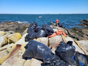 Trash bags full of marine debris piled on a rocky island shoreline